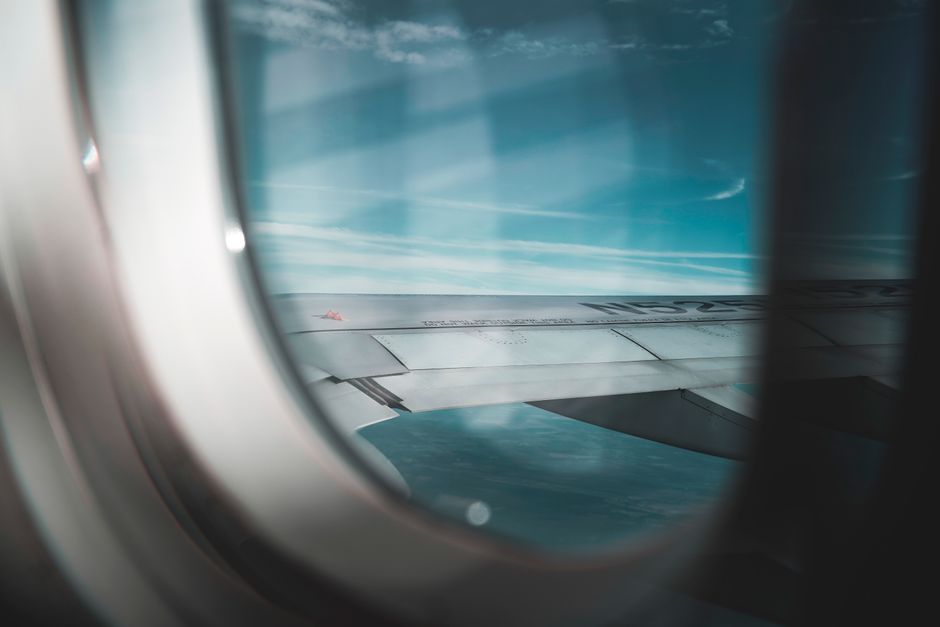 A serene view of an airplane wing against a backdrop of blue sky from a window seat.